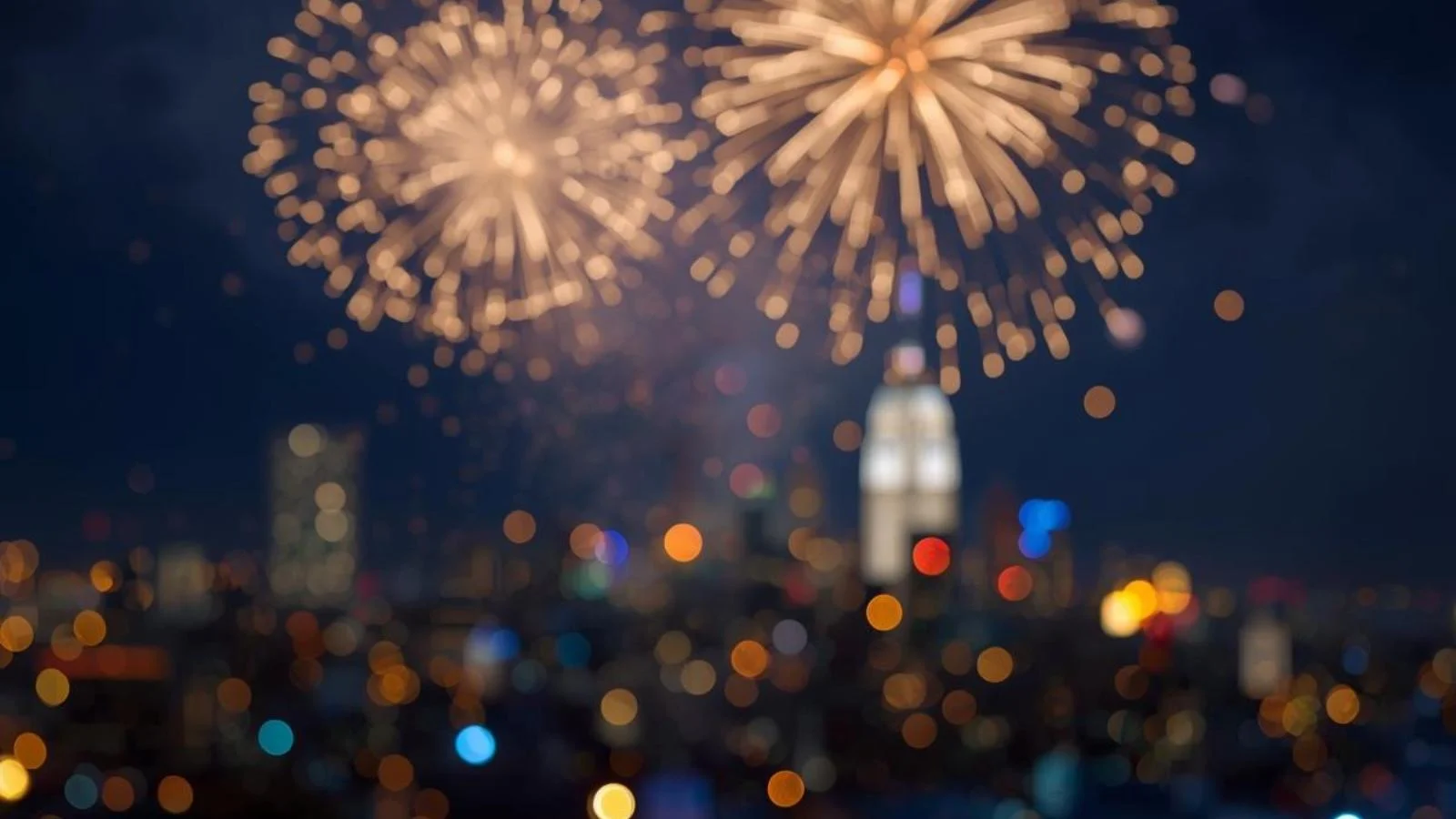 Fireworks lighting up a city skyline at midnight for a New Year celebration.